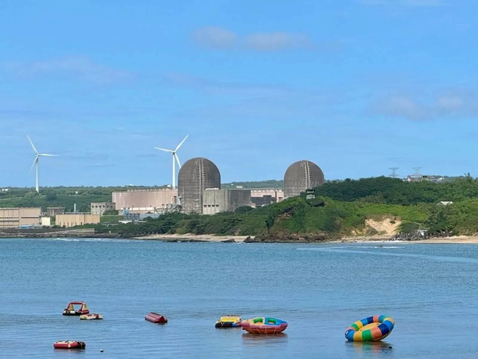 南灣是墾丁戲水勝地,海面上漂浮著水上活動業者的器材,遠方可以清楚看到核三廠反應爐圍阻體。資料照。攝影:李蘇竣