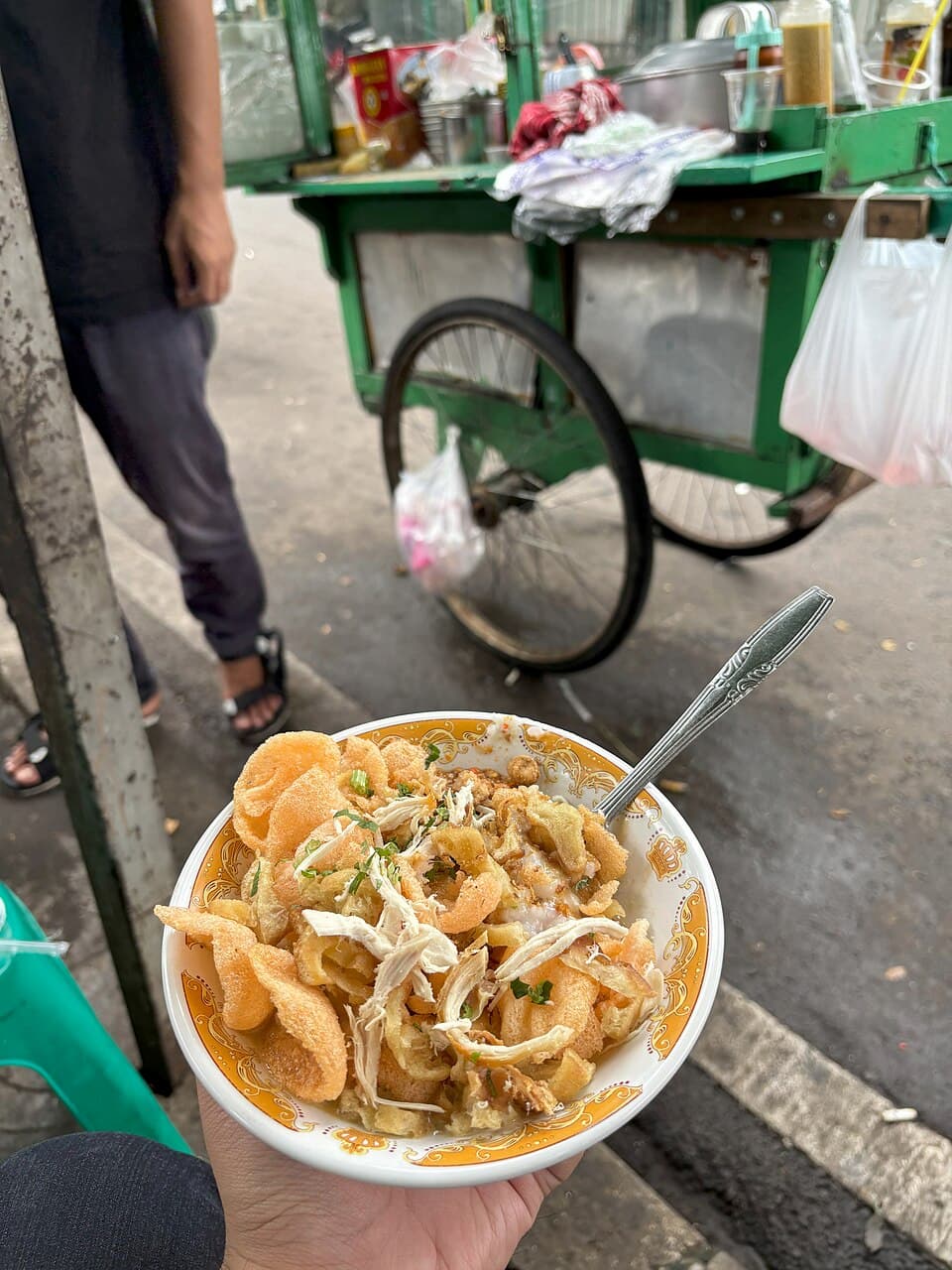 Chicken porridge served in a ceramic bowl with a stainless steel spoon from a street vendor in Jakarta in 2024. Image courtesy of David Wadie Fisher-Freberg/Wikimedia Commons.